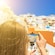 A woman photographing houses in Santorini on her smart phone using a selfie stick